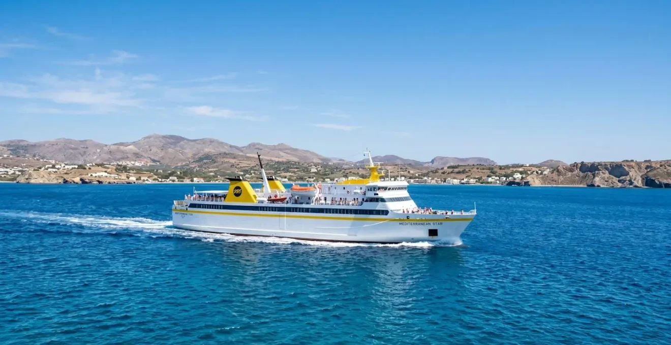 Ein modernes weiß-gelbes Fährschiff von Corsica Ferries fährt bei strahlendem Sonnenschein über das tiefblaue Mittelmeer mit Küstenlandschaft im Hintergrund